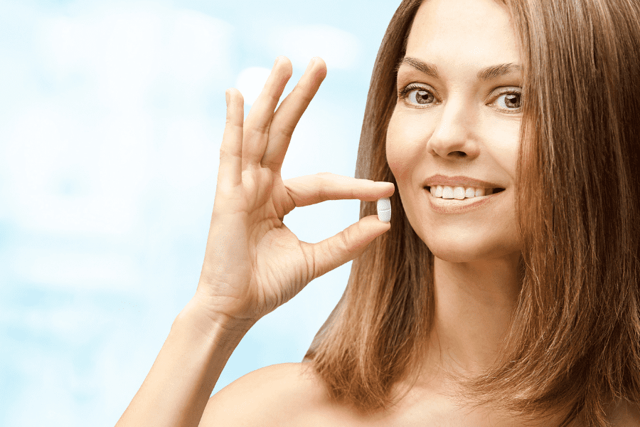 Ragazza sorridente con pillola di magnesio.